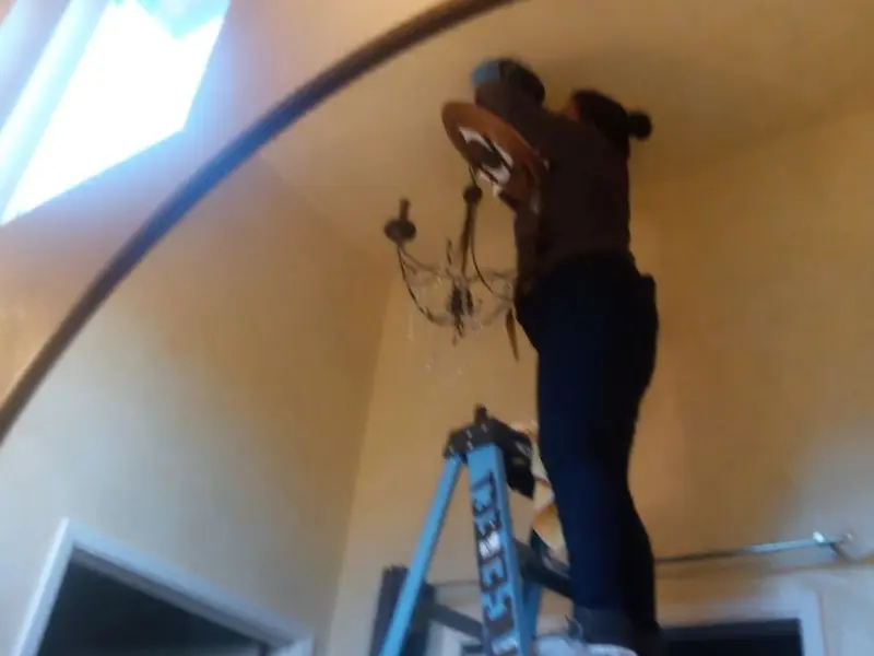 Electrician installing a chandelier in a Athens residence
